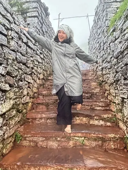 A happy trekker on the stone steps of a fort in Chikmagalur, enjoying the rainy weather.