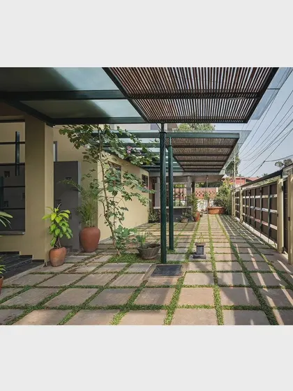 The driveway and entrance area are designed as a semi-open space that blends with the landscape. The stone pavers with grass joints create a permeable surface that connects the built form with the surrounding greenery.