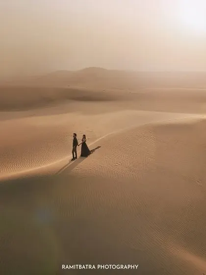 Two souls, alone in the vast, golden expanse of the Thar desert in Jaisalmer. This cinematic drone shot captures the epic scale and quiet intimacy of a pre-wedding story, where the landscape is as much a character as the couple themselves.