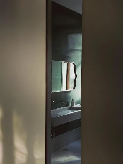 A glimpse into a bathroom featuring our custom "bracket mirror" and a handcrafted in-situ sink made of green terrazzo and white marble. Every element is designed to work in harmony.