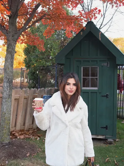 A cheerful pose in a white teddy coat against the vibrant fall foliage at Blue Mountain.