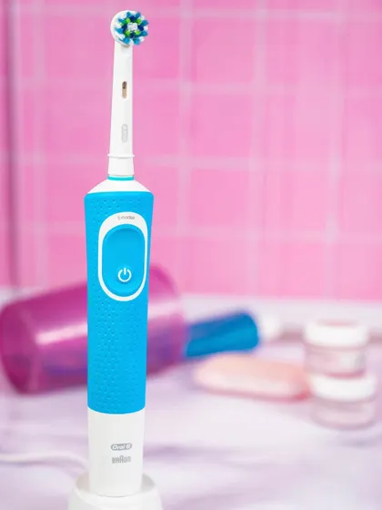 A close-up of the Oral-B electric toothbrush with the brush head attached, ready for use. This action-oriented shot helps customers understand the product's functionality at a glance.