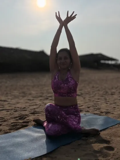 In Gomukhasana, or cow face pose arms, I reach towards the sky as the sun sets over the ocean. This pose stretches the shoulders and chest, and the golden light adds a layer of warmth and healing to the practice.
