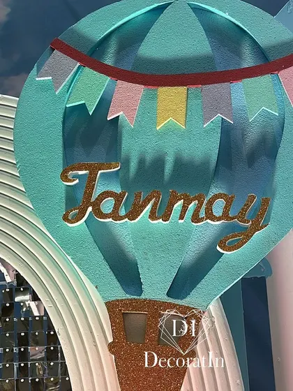 A close-up of a custom hot air balloon prop with the name "Tanmay" in glittery letters.