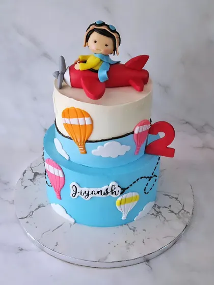 Chalo chalein! A two-tier chocolate truffle cake with a pilot theme for Jiyansh's 2nd birthday, featuring a cute figurine in an airplane.