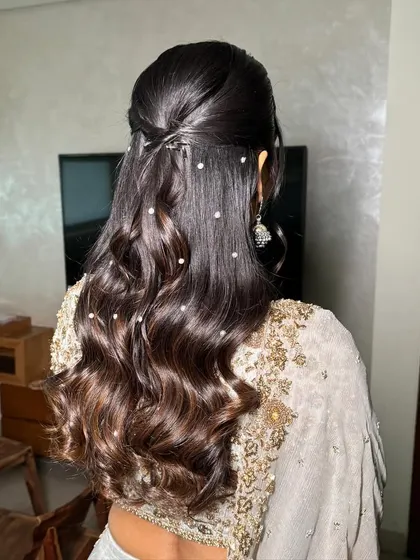 A detailed shot of the hairstyle. Soft Hollywood waves with delicate pearl accessories for a touch of glamour.