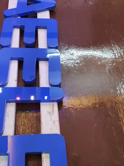 A close-up of the finished Duco-painted letters. The surface is so smooth and reflective you can see the light bouncing off it. This is the quality and attention to detail we bring to every Duco project.
