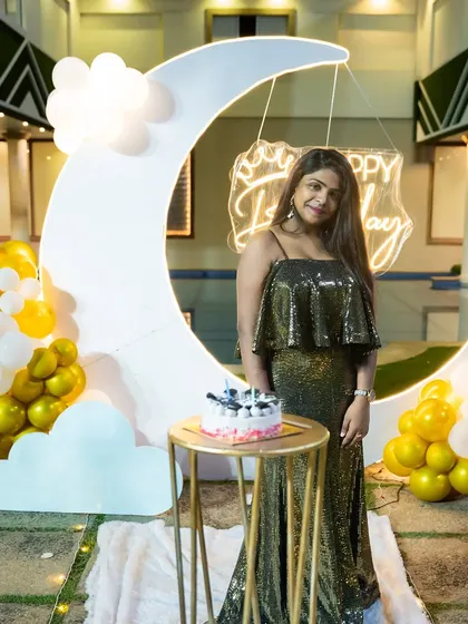 A close-up of the birthday girl with her cake in front of the moon backdrop. We can customize the neon sign to say 'Happy Birthday' or any other message.