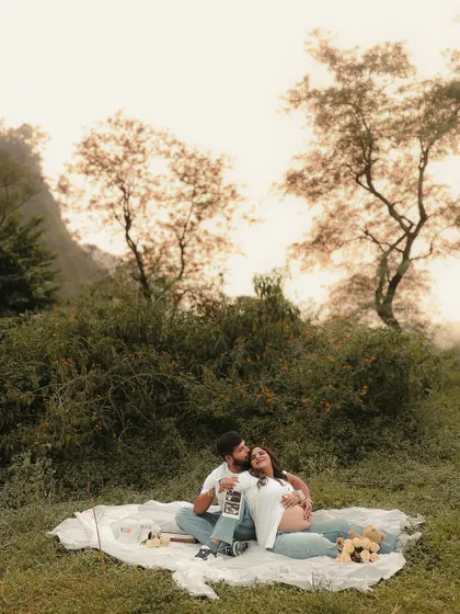 The couple shares a quiet moment during their outdoor picnic, looking at their baby's ultrasound picture together. This image beautifully captures their shared dream.