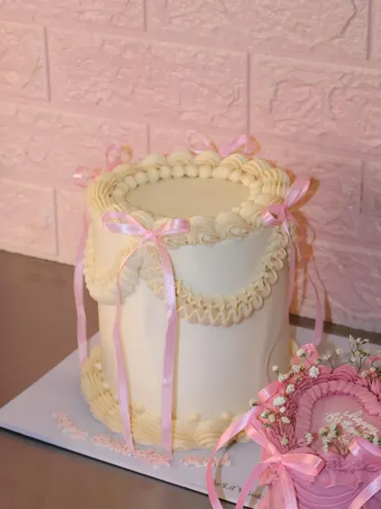This vintage-style cake gives us major princess vibes with its delicate piping and pretty pink ribbons. It's a beautiful example of our more intricate cake designs, perfect for a truly special celebration.