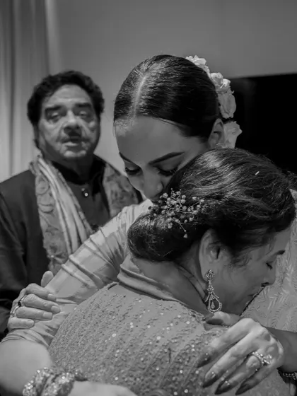 A bride shares a three-way hug with her parents just before walking to her groom. This black and white image beautifully captures the emotion and unity of the family in this significant moment.