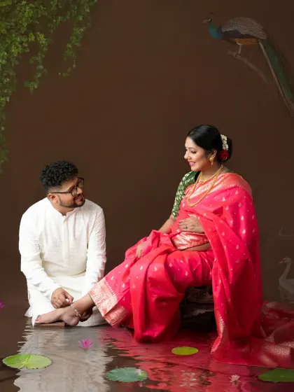 An artistic and romantic scene. The couple is set in a painterly landscape with water and lotus flowers, creating a truly unique and memorable portrait.