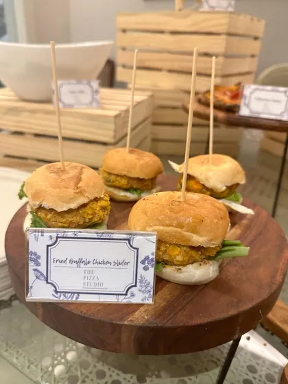 A close-up of our fried truffled chicken sliders. These bite-sized burgers are served on a wooden platter, each held together with a skewer, showcasing our attention to detail and gourmet flavor combinations.