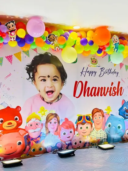 A close-up of the personalized Cocomelon backdrop and colorful balloon garland.