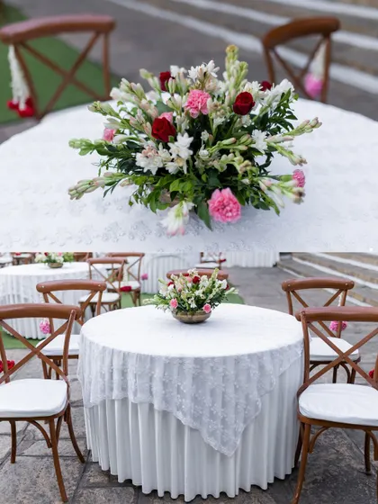 A beautiful floral centerpiece of roses, carnations, and tuberoses on a lace-covered round table. We believe that elegant table scapes are key to a refined guest experience.