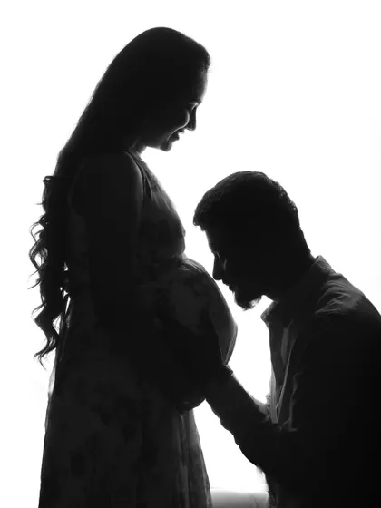 A beautiful silhouette of a partner kissing the baby bump. This black and white image is so intimate and full of love, a perfect artistic memory of the pregnancy journey.