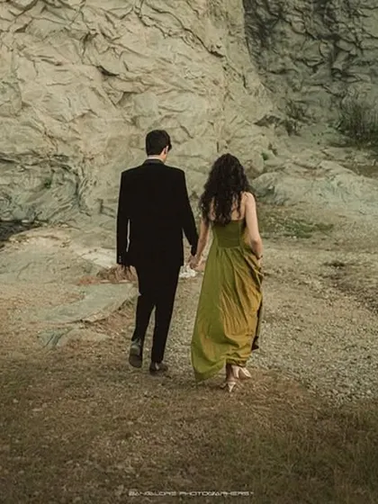A dramatic pre-wedding shot of the couple walking in a vast, rocky landscape. It tells a story of adventure and journeying together.