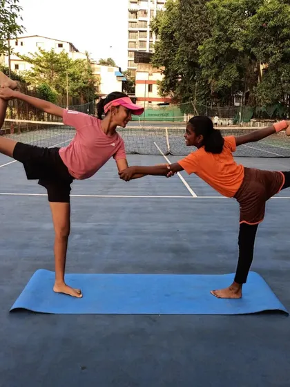 Partner yoga helps build trust and communication between players. This standing bow pose requires balance and coordination, reflecting the synergy needed in doubles play.