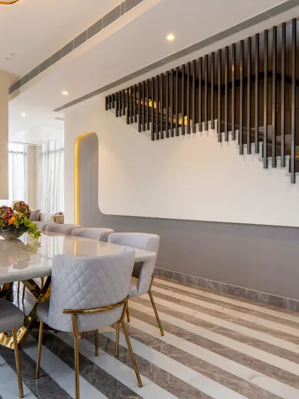 A detail shot of the dining area, showing the modern staircase with vertical metal railings. The design creates a visual connection between floors while maintaining an open and minimalist aesthetic.