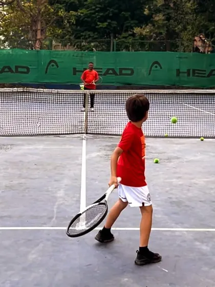 From mastering the basics to embracing brilliance, every swing is a step forward. A young player practices his returns with a coach.