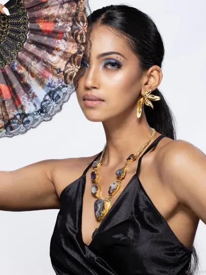 A portrait showcasing the model's jewellery and the fan as a prop.