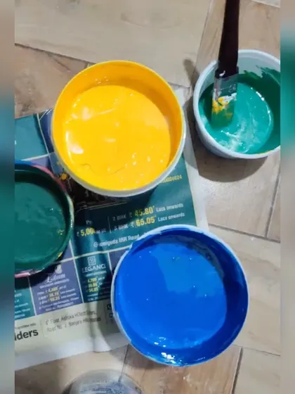 A top-down view of the vibrant paint colors chosen for a floral mural project. The selection of bright yellow, deep green, and bold blue sets the tone for an energetic and happy piece of wall art.