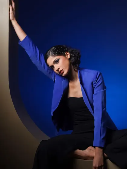 A dramatic pose within a circular frame, using a deep blue background. The composition is strong and graphic, perfect for a magazine feature.