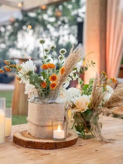 A rustic centerpiece on a wooden table, combining burlap, candles, and wildflowers for an earthy, natural feel.