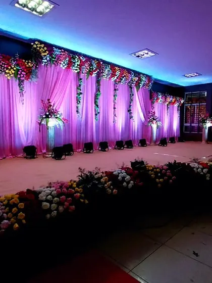 Here, I used lighting to completely transform the mood of the venue. The purple and blue hues on the draped backdrop, combined with hanging floral elements, create a vibrant and celebratory atmosphere.