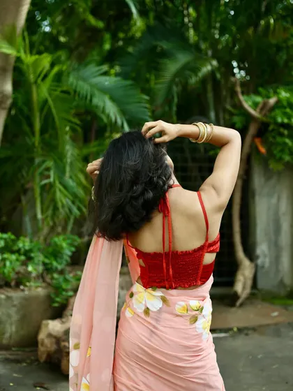 A back-profile shot that highlights the stylish design of the blouse and the flow of the saree, useful for showing garment details.