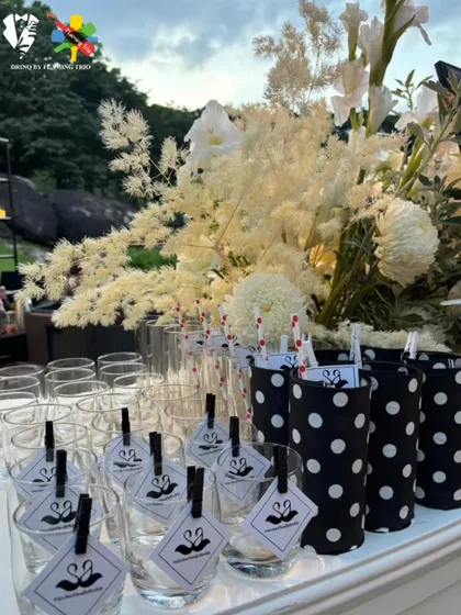 Personalized glassware with custom tags and polka-dot sleeves, set against a backdrop of white florals. These details showcase our commitment to creating a fully branded and beautiful bar experience.