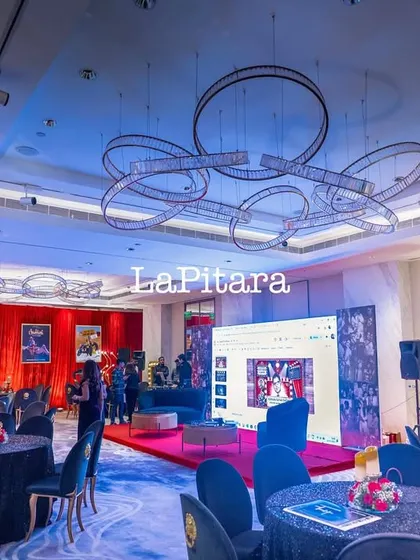 A wide shot of the Bollywood party venue, showing the stage, dining area, and modern ring chandeliers that add a touch of contemporary style.