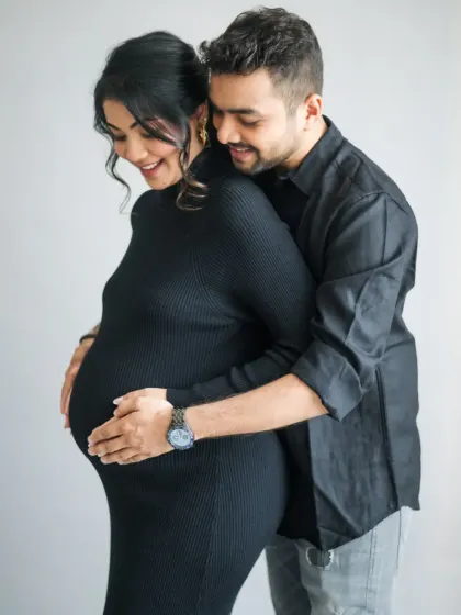 A timeless portrait of an expecting couple. The classic pose, with his arms wrapped around her, creates a feeling of love, support, and shared anticipation.