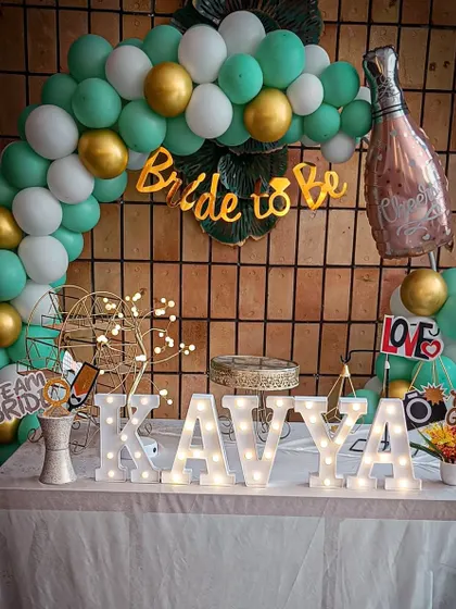 A chic and simple 'Bride to Be' decoration with a mint green and gold balloon arch and a champagne bottle balloon.