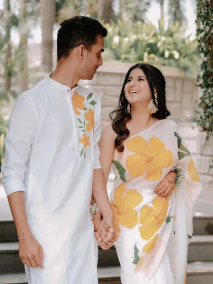 Divya and Chaitanya look lovingly at each other, their matching floral outfits perfectly complementing the garden setting. This is a great example of a bright and happy pre-wedding portrait.