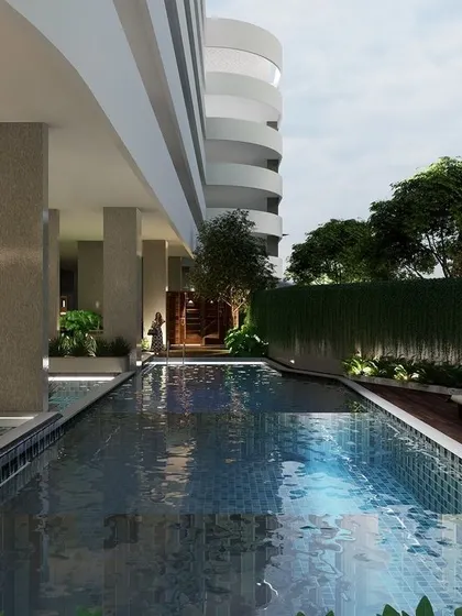 The luxurious swimming pool at Marian Park is designed for relaxation. It is flanked by a wooden deck and a green wall, creating a resort-like atmosphere within the apartment complex.
