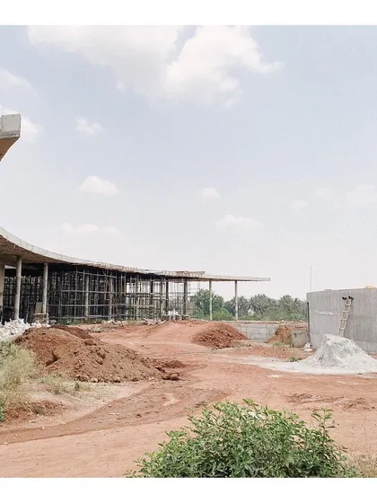 The curved roof of the auditorium building under construction, with its supporting columns exposed. This image shows the skeletal structure of the building against the sky, revealing the elegance of its form.