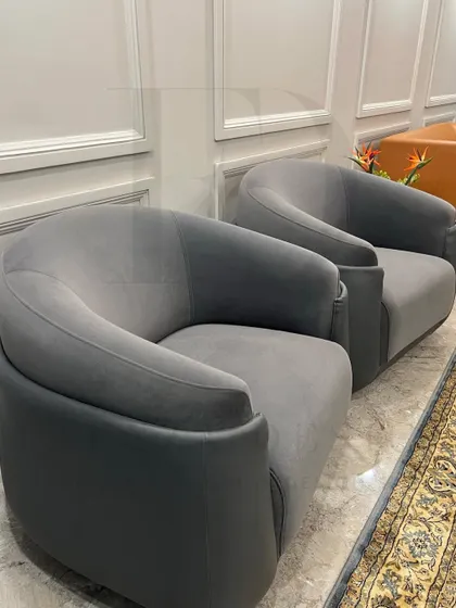 These custom-made barrel chairs in a soft grey velvet offer a comfortable and stylish seating solution. Their curved form provides a welcoming embrace, perfect for a conversation corner.