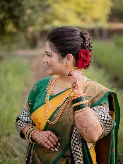 A stunning side profile of the bride, showcasing her intricate hairstyle with red roses, traditional jewelry, and radiant smile.