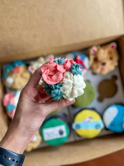 A mini bouquet of flowers piped onto a cupcake, part of a custom assortment.
