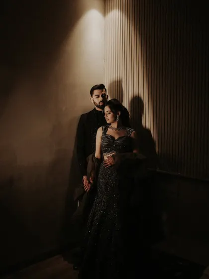 A moody and romantic portrait of the couple. The play of shadow and light creates an intimate atmosphere, highlighting their connection and the elegance of their Sangeet attire.