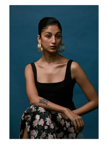 An editorial portrait for a jewelry brand. The bold blue background makes the gold earrings pop, while the model's direct gaze creates a strong connection.