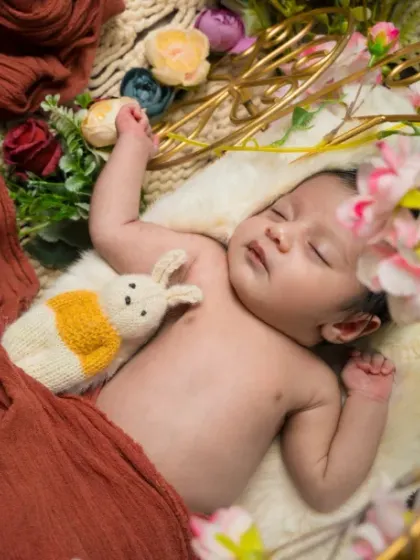 A garden of dreams. This overhead shot shows a baby sleeping peacefully, surrounded by flowers and holding a tiny stuffed bunny.
