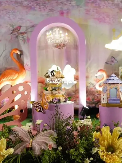 Samhita's enchanted garden party stage, featuring a whimsical backdrop with flamingos, butterflies, and a beautiful cake display. The mix of elements created a unique and vibrant look.