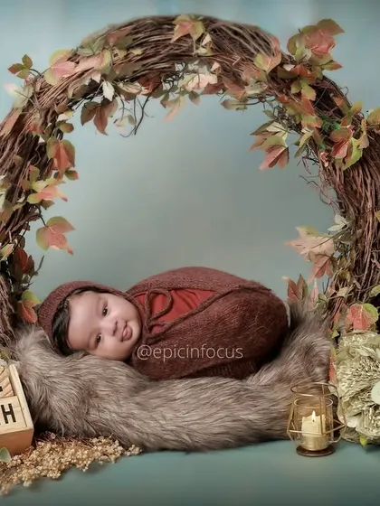 This two-month-old baby is nestled in a rustic, vine-covered wreath. We use natural elements and soft textures to create serene and artistic newborn portraits.