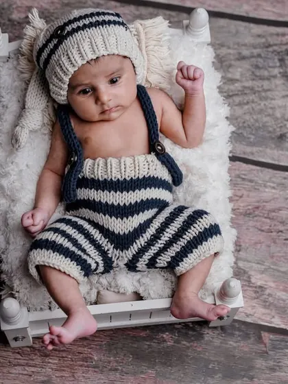A little sailor, wide awake. This photo captures the baby's curious expression in a cute, nautical-themed outfit.