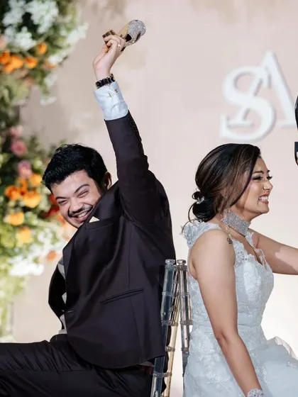The shoe game brings out the laughs during the reception. The lush floral wall behind the couple adds a touch of beauty and color to this fun-filled activity.