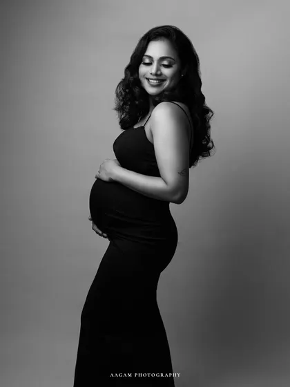 A joyful and candid-feeling black and white maternity portrait. Her smile is radiant, and the simple black dress is classic and chic.