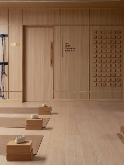 The yoga studio at BeWell in Amritsar, a study in the geometry of stillness. The space is defined by clean lines, warm wood paneling, and carefully organized equipment, creating a focused and uncluttered environment for practice.
