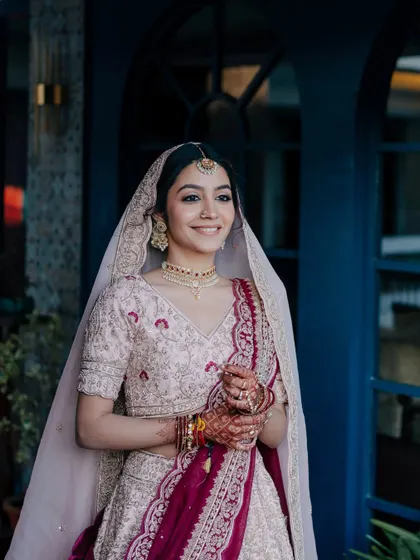 The magic of a first look. This bride's soft smile and glowing skin in her pastel lehenga create a moment of pure, unscripted joy.